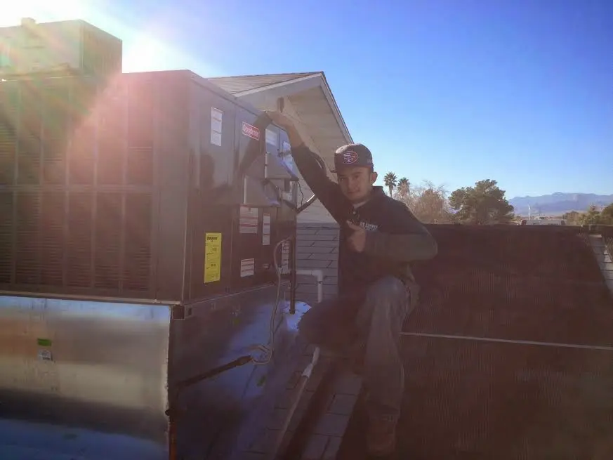 HVAC technician performing Air Duct Repair on a rooftop unit in Hubbard